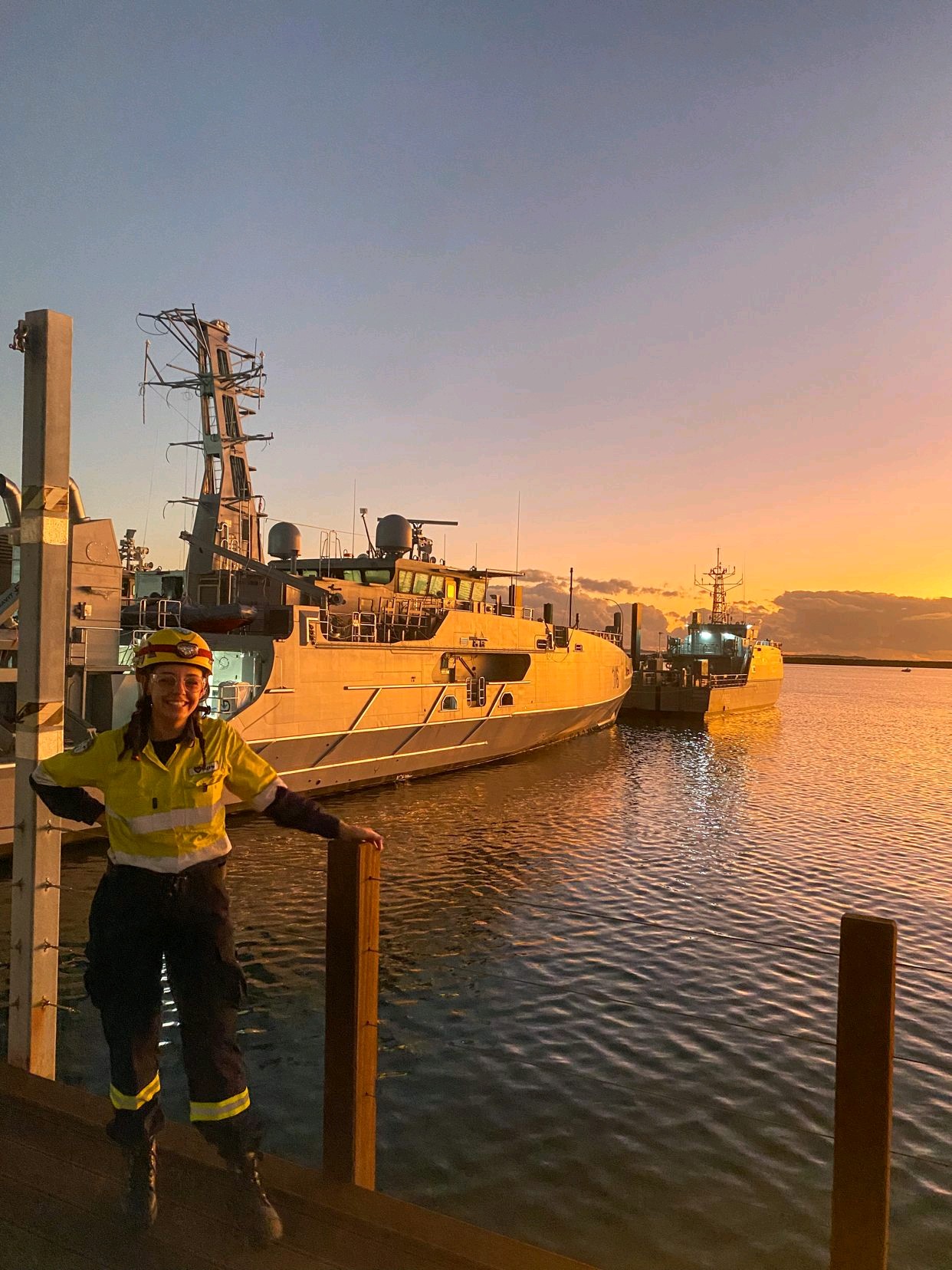 a woman posing on a dock with a patrol vessel