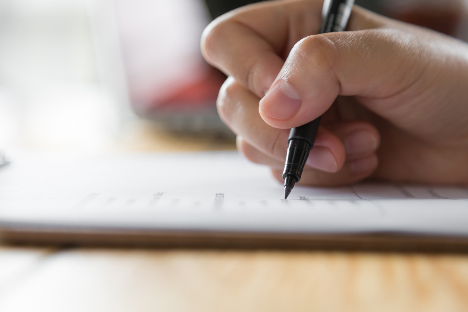 a person who holds a pen and is writing on paper