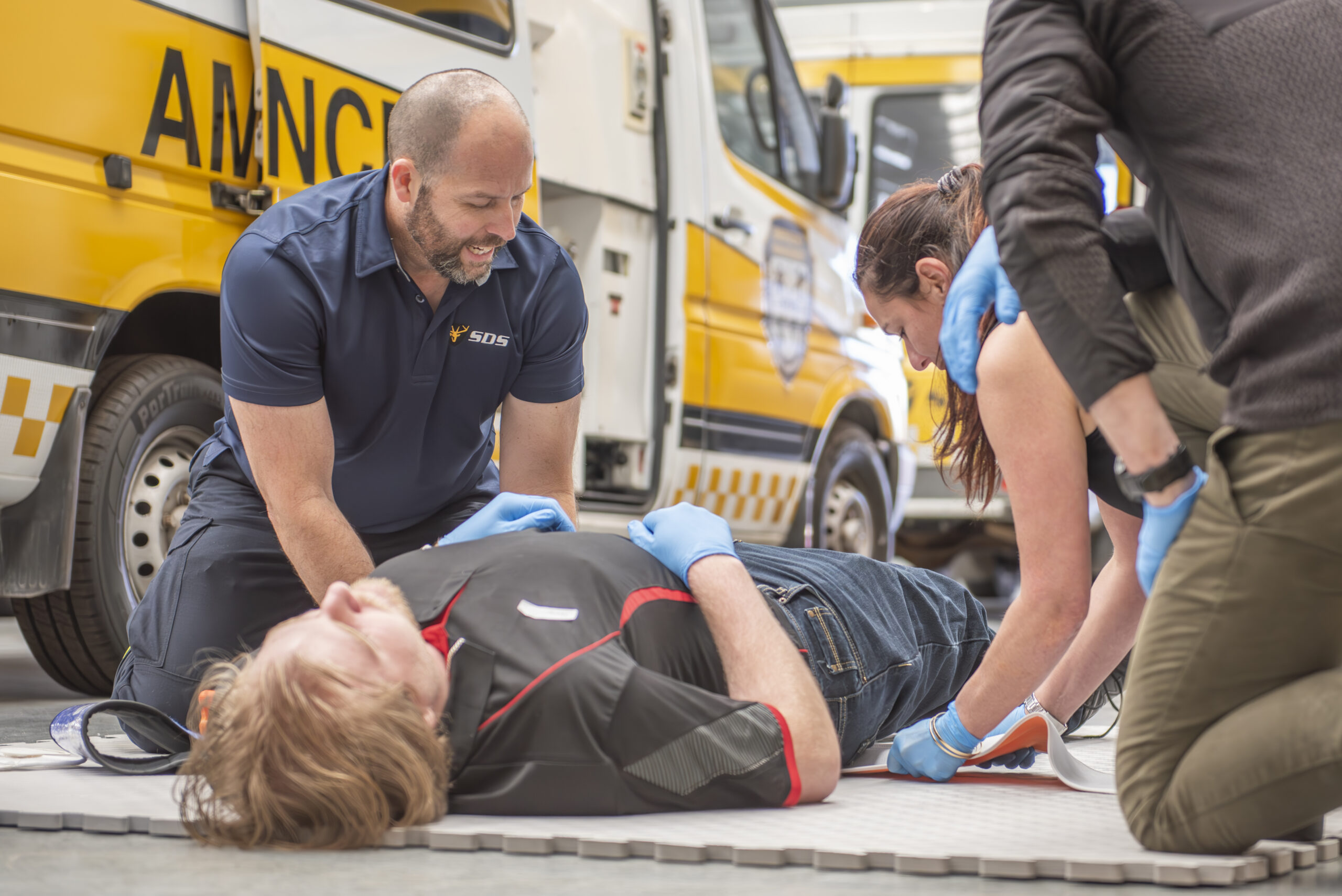a person who is lying on the street, and other people put a mat under him